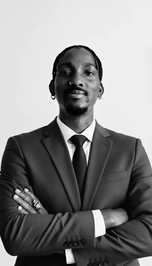 Adeilé in a dark suit, arms folded
